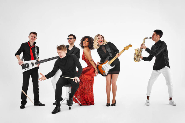 photo of multi ethnic music band in studio.Musicians and woman soloist posing over white background - Foto, imagen
