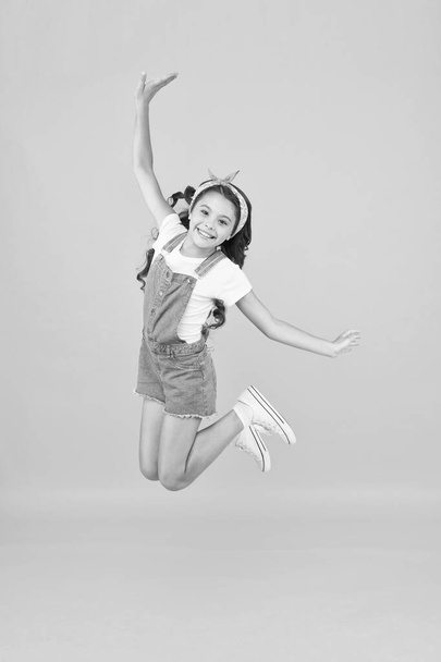 Small girl jump yellow background. Enjoy freedom. Childrens day concept. Spirit of freedom. Active girl feel freedom. Fun and relax. Feeling free. Carefree kid. Summer holidays. Jump of happiness - Photo, image