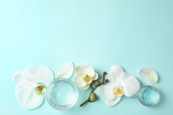 Flat lay composition with cosmetic gel and beautiful flowers on light blue background. Space for text - Foto, Imagem