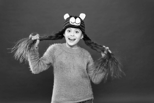 Winter care for long hair. Cute accessories. Adorable baby long hair wear cute winter knitted hat. Girl wear winter theme accessory. Fun and joy. Festive spirit. Cheerful smiling kid. Playful cutie - Foto, immagini