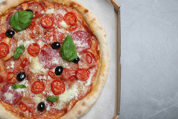 Delicious pizza Diablo in cardboard box on grey table, top view - Фото, изображение