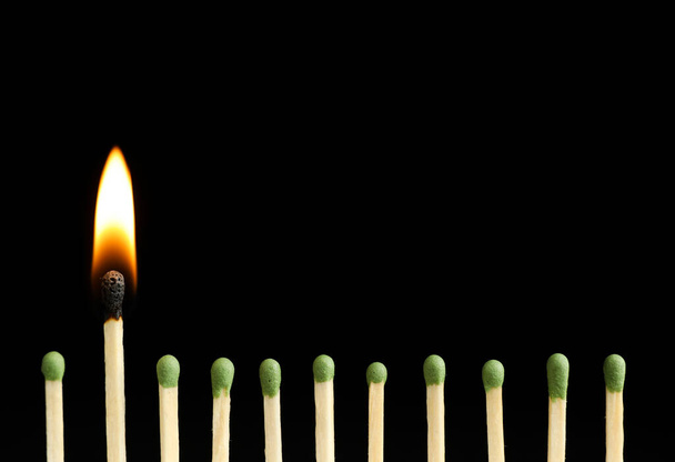 Burning match among unlit ones on black background, closeup - Фото, зображення
