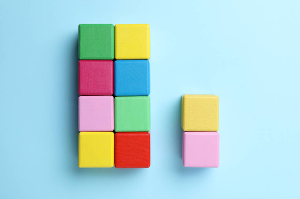 Flat lay composition with colorful cubes on light blue background. Pareto principle concept - Foto, Bild