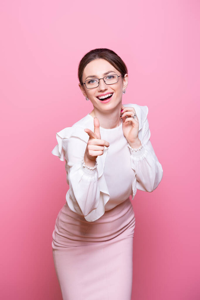Smiling young businesswoman in glasses motivates success with positive gestures. Isolated on pink background. - Foto, imagen