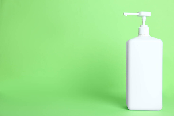 Dispenser bottle with antiseptic gel on green background. Space for text - 写真・画像