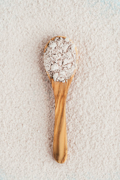 Pink clay in a wooden spoon on a pink, white background. - Fotoğraf, Görsel