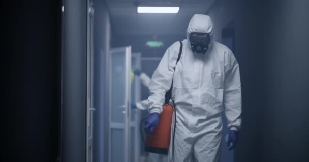 Hombres con trajes de materiales peligrosos desinfectando el edificio
 - Imágenes, Vídeo