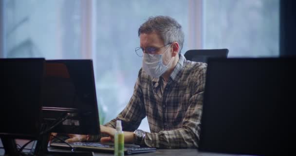 Face mask wearing man working in office - Video