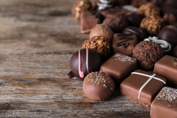 Different delicious chocolate candies on wooden table - Foto, afbeelding