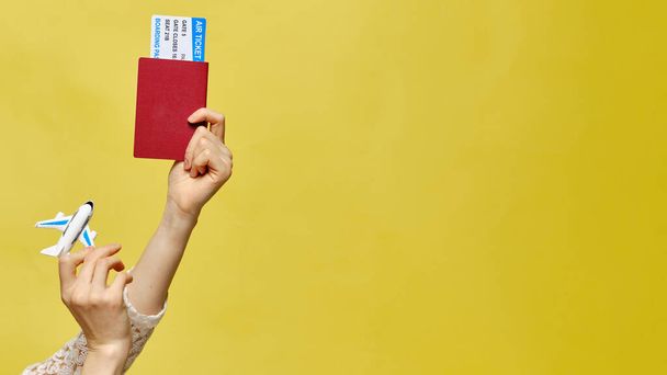 As mãos são levantadas e segurando bilhetes com um avião de brinquedo de passaporte em um fundo amarelo. Espaço para cópia. Fechar
. - Foto, Imagem