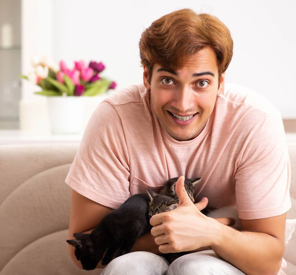 Młody mężczyzna bawi się z kotkiem w domu - Zdjęcie, obraz