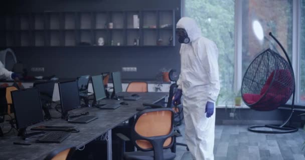 Hombres con trajes de materiales peligrosos desinfectando la oficina
 - Imágenes, Vídeo