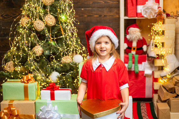 Cheerful cute child opening a Christmas present. Happy child decorating Christmas tree. Cute little child near Christmas tree. - Foto, Imagen