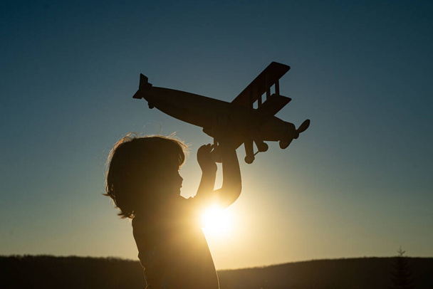 Child pilot aviator with airplane dreams of traveling. Child dreams. Child on the background of sunset sky. - Photo, Image