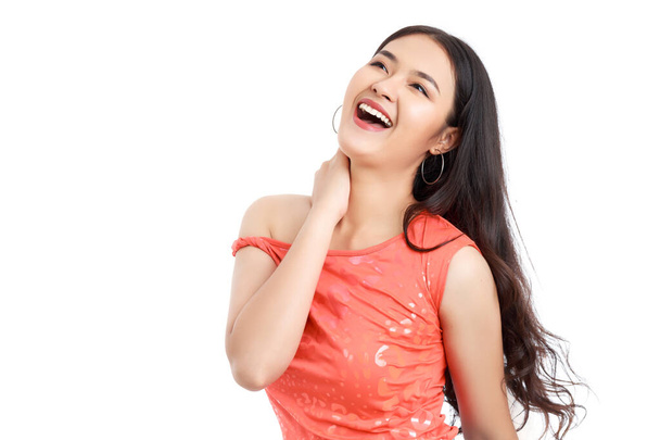 Młoda atrakcyjna Azjatka nosi pomarańczowy t-shirt przeskakując do przodu ze szczęśliwą uśmiechniętą twarzą odizolowaną na białym tle. - Zdjęcie, obraz
