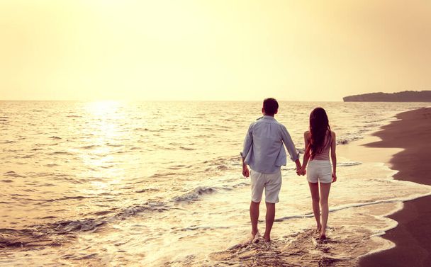giovane coppia passeggiando sulla spiaggia al tramonto - Foto, immagini