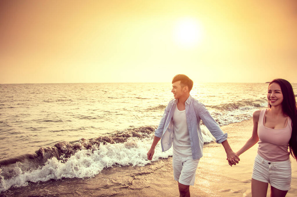 happy asian young couple walking on the beach at sunset - Foto, immagini
