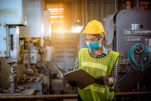 Portrait woman worker under inspection and checking production process on factory station by wearing safety mask to protect for pollution and virus in factory. - 写真・画像