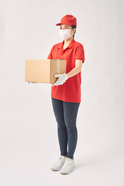 Доставка женщина держит картонные коробки в медицинских резиновых перчатках и маске на белом фоне
.  - Фото, изображение