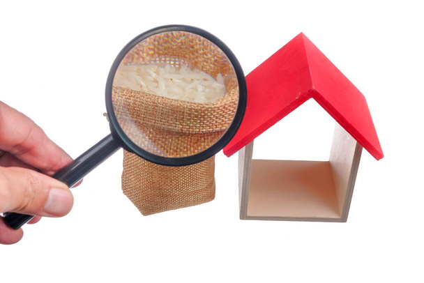 Rijst in de zak, vergrootglas en mini-huis geïsoleerd op witte achtergrond. Moslim concept voor zakat eigendom, inkomen en "Fitrah" zakat. - Foto, afbeelding