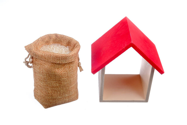 Reis im Sack und Mini-Haus isoliert auf weißem Hintergrund. Muslimisches Konzept für Zakat Eigentum, Einkommen und "Fitrah" Zakat. - Foto, Bild