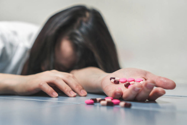 Suicide prevention concept, Close up hand of young asian woman taking medicine overdose trying to kill herself. - 写真・画像