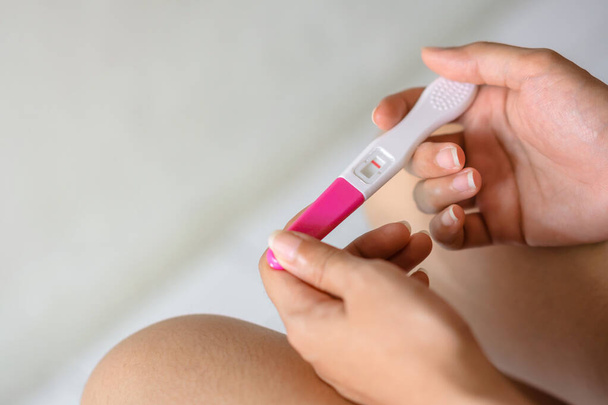 Unhappy young asian woman holding pregnancy test showing a negative result in her bathroom, wellness and healthy concept, infertility problem,Selective focus. - Photo, Image