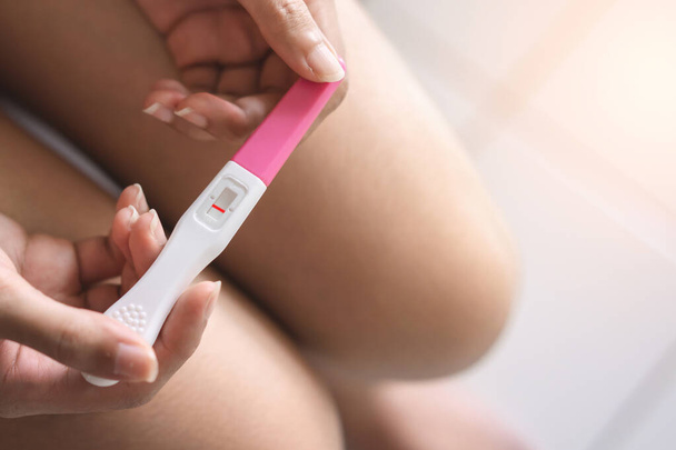 Unhappy young asian woman holding pregnancy test showing a negative result in her bathroom, wellness and healthy concept, infertility problem,Selective focus. - Photo, Image