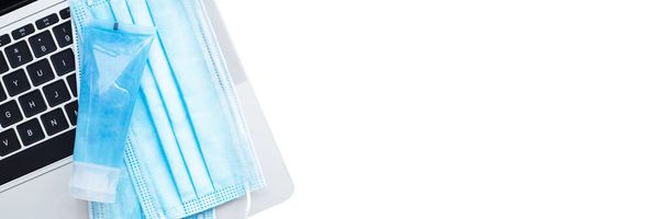 alkoholový gel dezinfekční a ochranné masky obličeje na klávesnici notebook izolované na bílém pozadí. nápis - zdraví a pracovní koncepce. - Fotografie, Obrázek