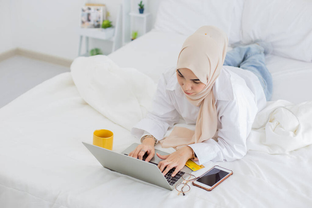 Asiatico bella musulmana giovane donna che lavora con il computer portatile a casa, comunica su internet, il lavoro dal concetto di casa
. - Foto, immagini