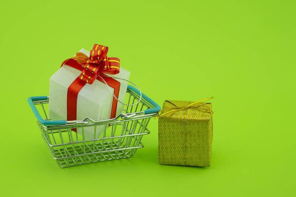 Winkelen voor cadeaus concept met winkelmandje en geschenken met decoratieve rode linten - Foto, afbeelding