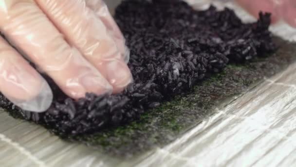 Šéf dává černou rýži na nori a dělá sushi roll ve zpomaleném filmu - Záběry, video