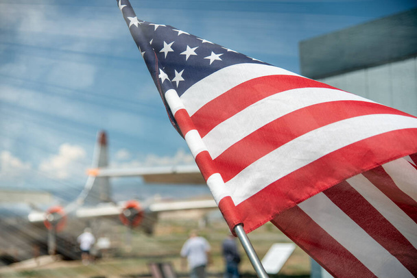 Κυματίζει αμερικάνικη σημαία με αεροσκάφη στο βάθος. Ταξίδι και πατριωτισμός. - Φωτογραφία, εικόνα