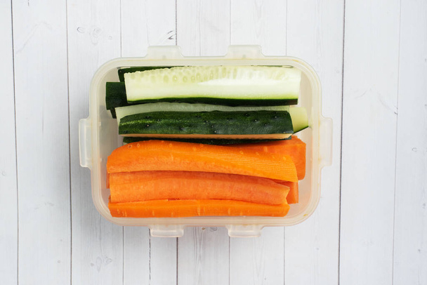 Fresh carrot and cucumber sticks in a container. Centimeter measurement of volume. Concept of dietary nutrition. Copy space - Foto, immagini
