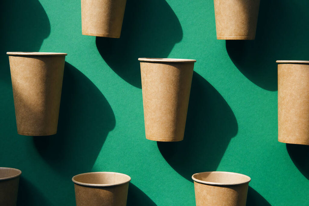 Экологически чистые ремесленные бумажные чашки на зеленом фоне. Концепция переработки. Тема нулевых отходов
 - Фото, изображение