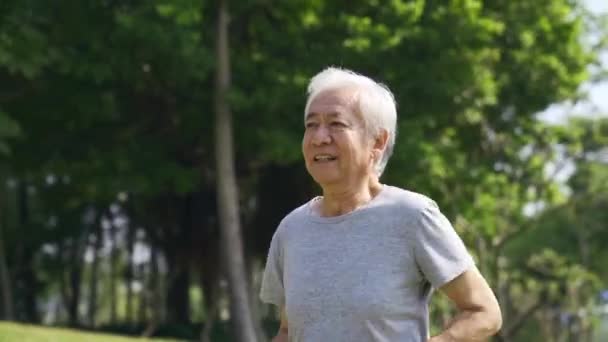 šťastný asijský starý muž cvičení jogging venku v parku - Záběry, video