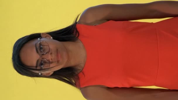 Mixed-race young woman spreading her hands to the sides and saying "what" on yellow background - Imágenes, Vídeo