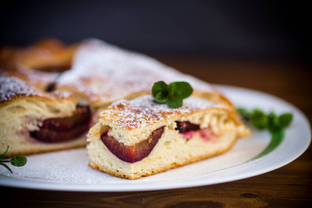 sweet baked homemade plum cake with icing sugar on a wooden table - Foto, immagini