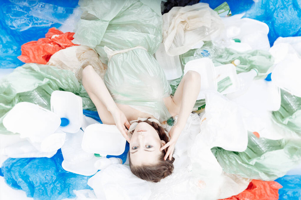 A beautiful girl of European appearance is lying on a mountain of plastic.  - Foto, afbeelding