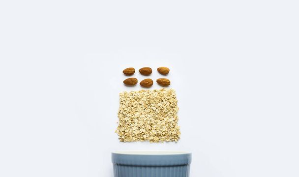 Oatmeal, almonds, wood spoon on a white background. View from above. Proper meals and breakfast. Falt lay. Place for text - 写真・画像