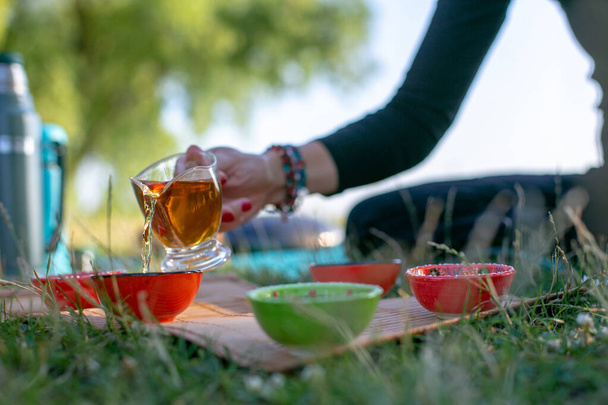 жінка в чорній блузці розливає зелений чай на мисках на пікнік
 - Фото, зображення