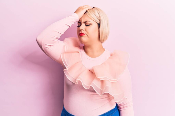 Young beautiful blonde plus size woman wearing casual sweater over isolated pink background surprised with hand on head for mistake, remember error. Forgot, bad memory concept. - Valokuva, kuva