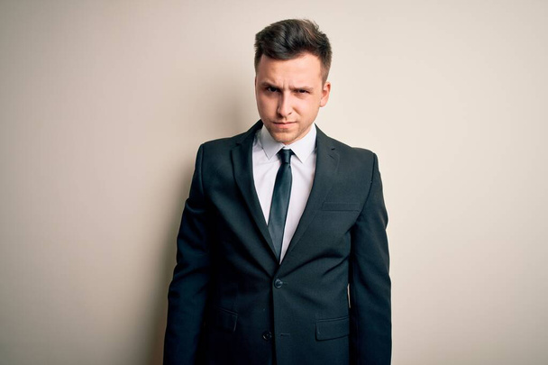 Young handsome business man wearing elegant suit and tie over isolated background skeptic and nervous, frowning upset because of problem. Negative person. - Photo, Image