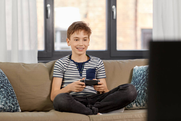 boy with gamepad playing video game at home - Zdjęcie, obraz