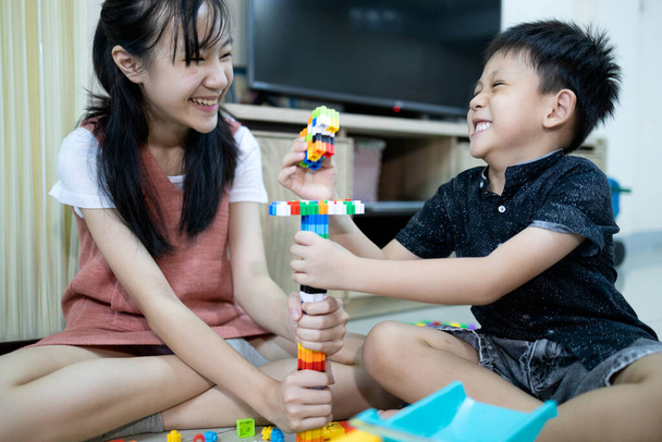 Sorella asiatica felice e sorridente fratellino che gioca con giocattoli colorati insieme a casa, bambino dell'asilo e bambina che si divertono, godono, ridono felicemente, giocattoli educativi, sviluppo per i bambini
 - Foto, immagini
