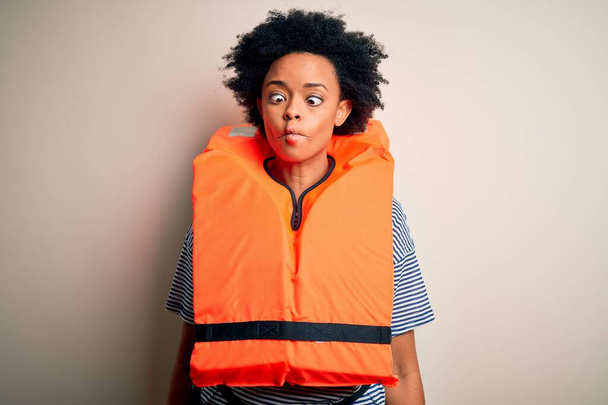 Fiatal afro-amerikai nő göndör haj visel narancssárga védő mentőmellény, hogy hal arc ajkak, őrült és komikus gesztus. Vicces kifejezés.. - Fotó, kép