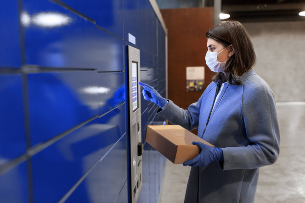 woman in mask with box at parcel machine - Foto, Bild