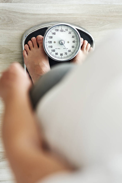 Vertical image of woman standing on a bathroom scale - Photo, Image