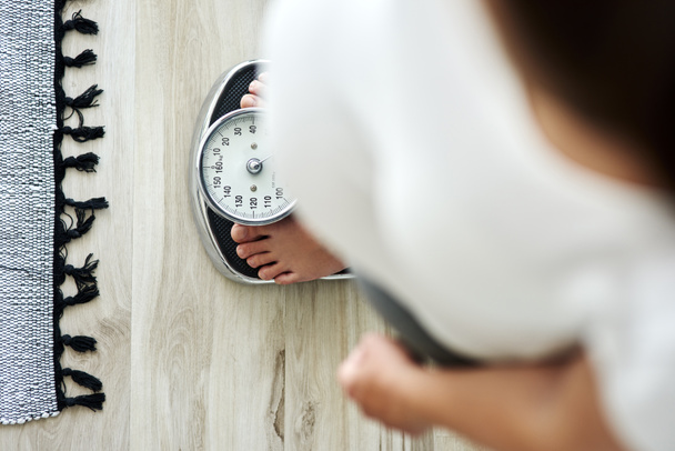 Horizontal image of woman standing on a bathroom scale - Photo, Image