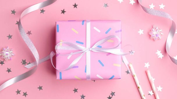Pink gift box with silver streamers and confetti stars on pastel pink background. Present for girl birthday, Valentines Day, anniversary. Flat lay, top view. - Foto, afbeelding